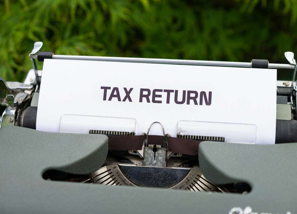 a close up of a typewriter with a tax return sign on it