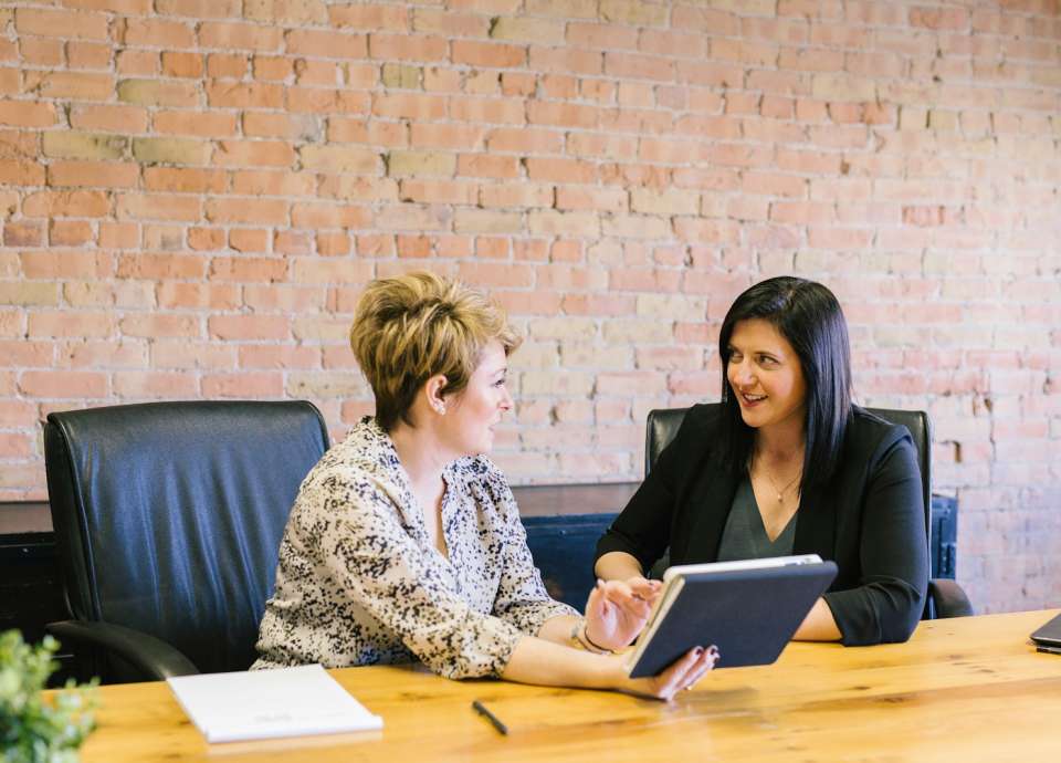 two women sitting on leather chairs in front of table